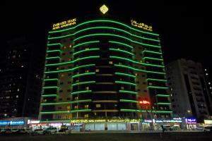 迪拜迪拜酋长星级公寓酒店的一座高大的建筑,晚上有绿灯
