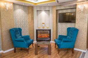 伯萨Ruba Palace Thermal Hotel的客厅配有2把蓝色椅子和壁炉