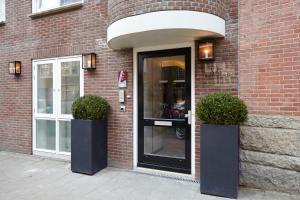 阿姆斯特丹阿姆斯特丹缪斯精品酒店的砖砌建筑的入口,有两株盆栽植物