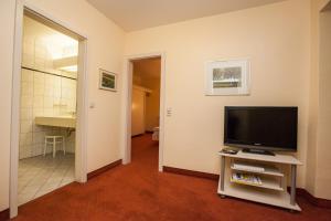 博帕德加尔尼古德酒店的带电视的客厅和浴室。