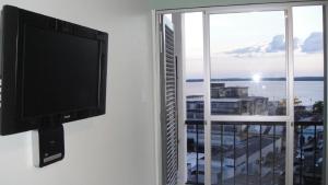 马瑙斯Ajuricaba Suites 1的挂在窗户旁墙上的平面电视