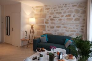 巴黎圣安娜花园公寓的客厅设有蓝色的沙发和石墙