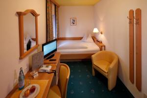 雷西亚Hotel Am Reschensee的酒店客房配有一张床和一张带电脑的书桌