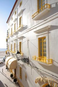 纳扎雷里巴马酒店的白色的建筑,设有黄色的窗户和阳台