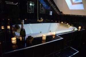 尼什Apartmani Vivaldi Niš的浴缸配有两瓶葡萄酒和蜡烛