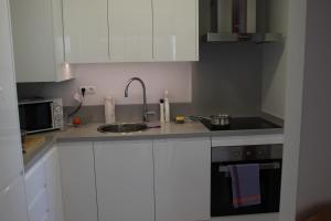 卡尔佩Amatista 12 D - Private的厨房配有白色橱柜、水槽和微波炉