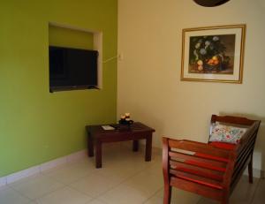 JinotepeLa Residencia Inn的客厅配有椅子、桌子和电视