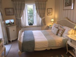 诺里奇Copperfields Guest House的一间卧室设有一张床、一个窗口和一台电视