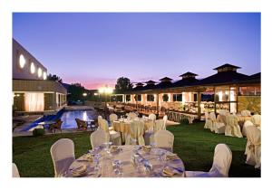 约阿尼纳塞瑟瑞亚酒店的一个带白色桌椅的宴会厅和一个游泳池