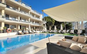 贝纳尔马德纳Vincci Selección Aleysa的酒店游泳池设有椅子和白色遮阳伞