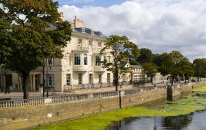 贝德福德Bedford Swan Hotel and Thermal Spa的一条大白楼,毗邻一条河流