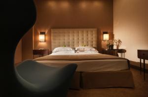 代森扎诺-德尔加达公园酒店的一间卧室配有一张大床和一把椅子