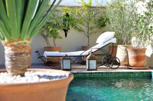 马拉喀什摩达摩洛哥传统庭院住宅的游泳池旁的一张床位,种植了植物