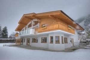 滨湖采尔滑雪和高尔夫​​所卡普伦出租小屋公寓的雪中带木屋顶的房子
