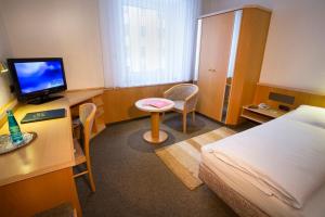 慕尼黑乔克酒店的酒店客房配有一张床和一张书桌及一台电视