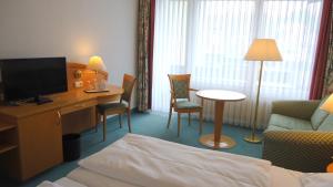 班贝格Hotel Altenburgblick的酒店客房配有一张床和一张书桌及一台电视