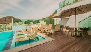 里约热内卢美洲科帕卡巴纳酒店 的一个带椅子和桌子的游泳池以及一把遮阳伞