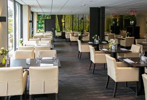 德布尔特迪斯弗莱彻酒店的用餐室配有桌子和白色椅子