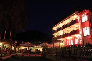 亚戈迪纳Yagodina Family Hotel的一座有灯光的建筑,人们在晚上坐在外面