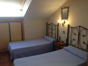 圣马丁德拉韦加Hostal San Martin的一间卧室设有两张床,墙上设有一面镜子