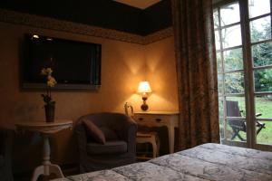 康布雷精艺轩酒店的一间卧室配有一张床、一把椅子和电视