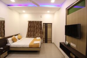 孟买黄金酒店的一间卧室配有一张床和一台平面电视