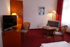格赖夫斯瓦尔德Hotel Am Dom的配有电视和桌椅的酒店客房