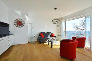 萨斯尼茨Suite Meersinn的客厅配有红色椅子和墙上的时钟