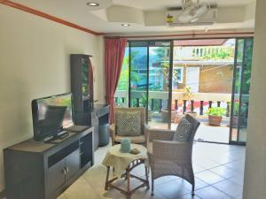 芭东海滩蓝天公寓式酒店的客厅配有平面电视和椅子