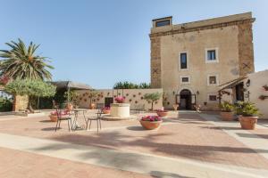 圣莱昂Hotel Foresteria Baglio Della Luna的一个带桌椅的庭院和一座建筑