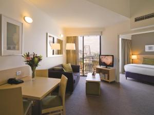 布里斯班Oakbridge Hotel & Apartments Brisbane的酒店客房设有床和客厅。