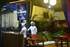 帕特南Om Shanti Beach Stay Patnem的两名厨师站在带桌椅的房间