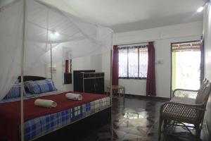 帕特南Om Shanti Beach Stay Patnem的一间卧室配有一张天蓬床和一把椅子