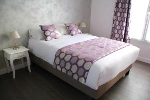 叙雷纳叙雷讷拉德芳斯舒适公寓式酒店的一间卧室配有一张大床,提供粉色和紫色枕头