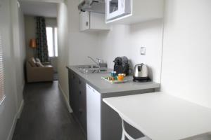叙雷纳叙雷讷拉德芳斯舒适公寓式酒店的白色的厨房配有柜台和水槽