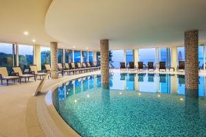 马林斯卡皮尼亚Spa康体酒店的酒店的大型游泳池配有桌椅