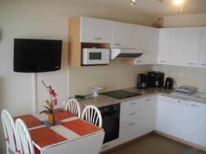 基伯龙Residence Front De Mer的厨房配有白色橱柜和桌椅