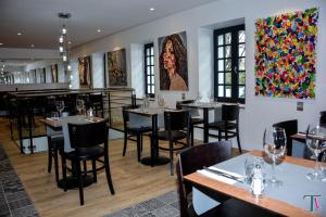波城Le Matisse Pau Centre的餐厅设有桌椅,墙上挂有绘画作品