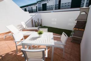 普拉亚布兰卡Apartamentos Quintana的阳台上配有白色的桌椅