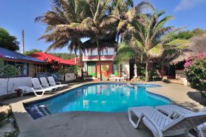 卡诺阿卡诺瓦酒店的一座房子前面的游泳池,游泳池里摆放着椅子和棕榈树