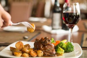 圣何塞Rincon del Valle Hotel & Suites的一块肉和蔬菜食品,一杯葡萄酒