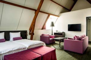 聚特芬聚特芬格雷芬霍夫罕布什尔酒店的一间卧室配有一张床、两把椅子和一台电视