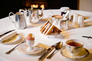 基拉尼杨梅酒店的一张桌子,上面有白色的桌布,上面有茶和甜点
