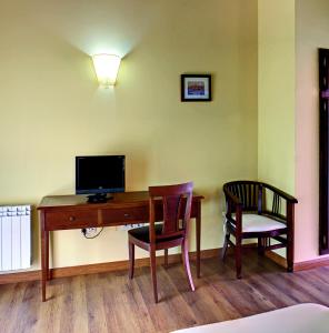 CoviellaHotel Rural Coviella的客房设有一张桌子、一台电视和两把椅子