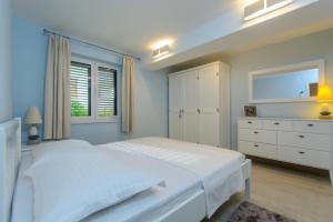 斯拉汀Luxury Apartment Kalebic的白色卧室设有一张大床和一个梳妆台