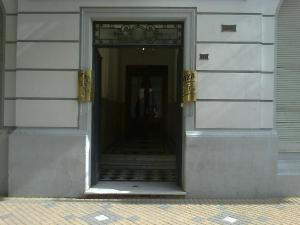 特雷斯阿罗约斯Hotel Plaza Tres Arroyos的通往大楼的门,大楼内设有楼梯