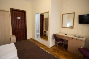 锡纳亚里奈科布尔酒店的酒店客房带一张床、一张书桌和一面镜子