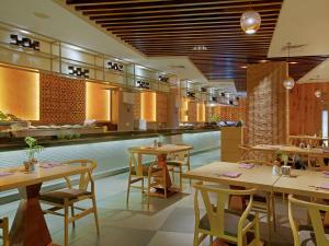 仰光仰光宾乐雅酒店的餐厅设有木桌、椅子和柜台