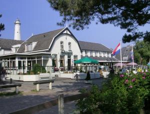 斯希蒙尼克奥赫山丘景观咖啡餐厅酒店的一座白色的大建筑,后面有一座灯塔