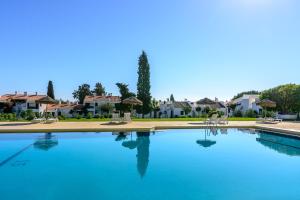 卡巴纳斯·德·塔维拉佩德拉达赖尼亚度假村的一座大型蓝色游泳池,其背景是房屋